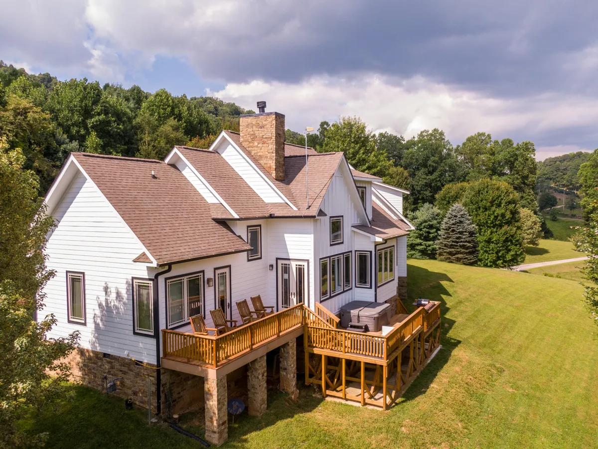 A welcoming wooden deck with large windows and stone accents overlooks the surrounding greenery, blending the comfort of home with close access to nature. The deck is ideal for relaxing or gathering after seasonal adventures.