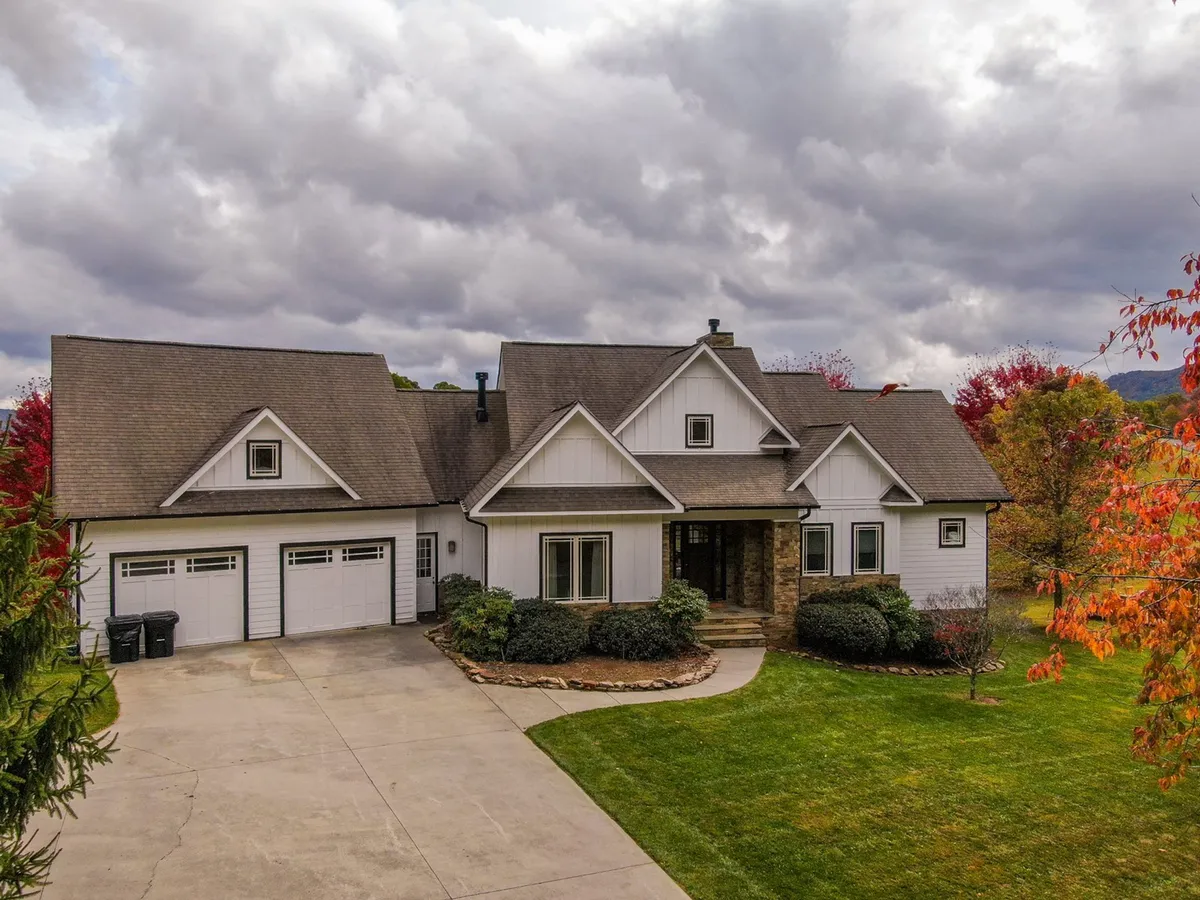 A welcoming front porch with stone accents, landscaped gardens, and garage doors set against a serene mountain backdrop. The porch invites relaxation and the lush garden space suggests ample room for pets and family to explore and unwind.