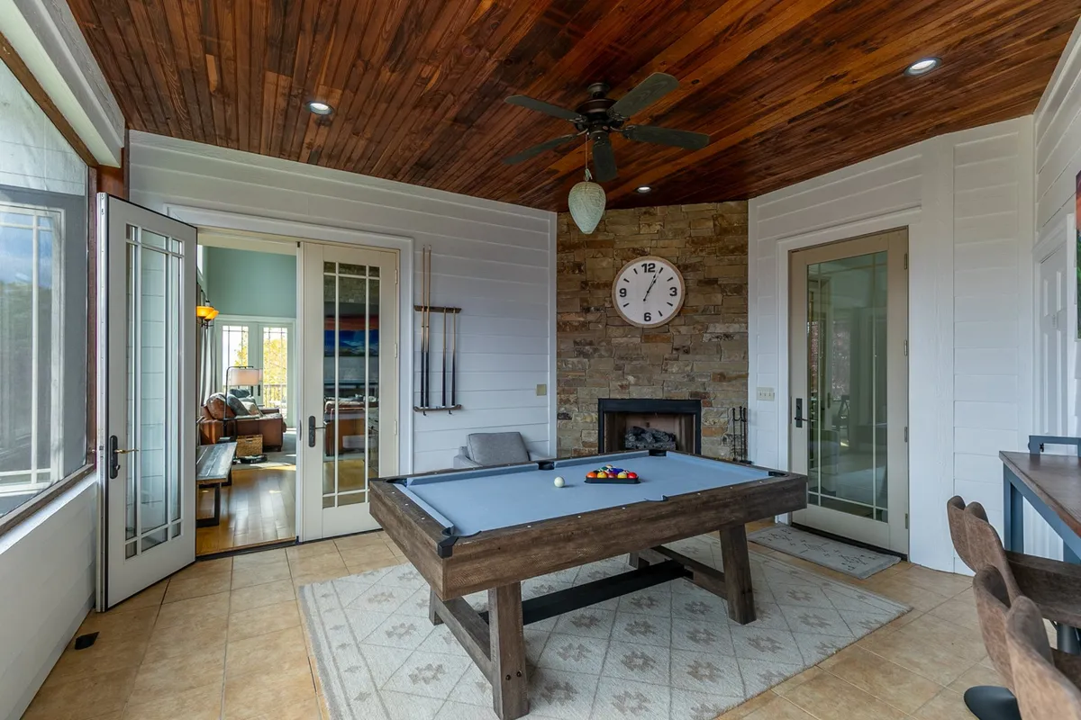 Inside, this image showcases a spacious room with a pool table, a fireplace, and a warm wooden ceiling. The mood is casual and friendly, evoking memories of friendly competition and celebratory moments.