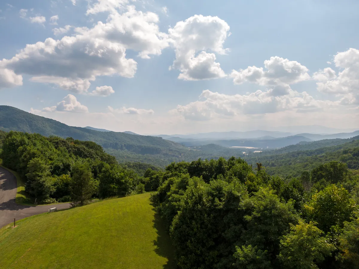 This scenic viewpoint features distant mountains, lush greenery, and a dramatic sky—offering a sense of adventure and the expansive outdoor experiences available nearby. The landscape hints at hiking, nature walks, and year-round exploration.